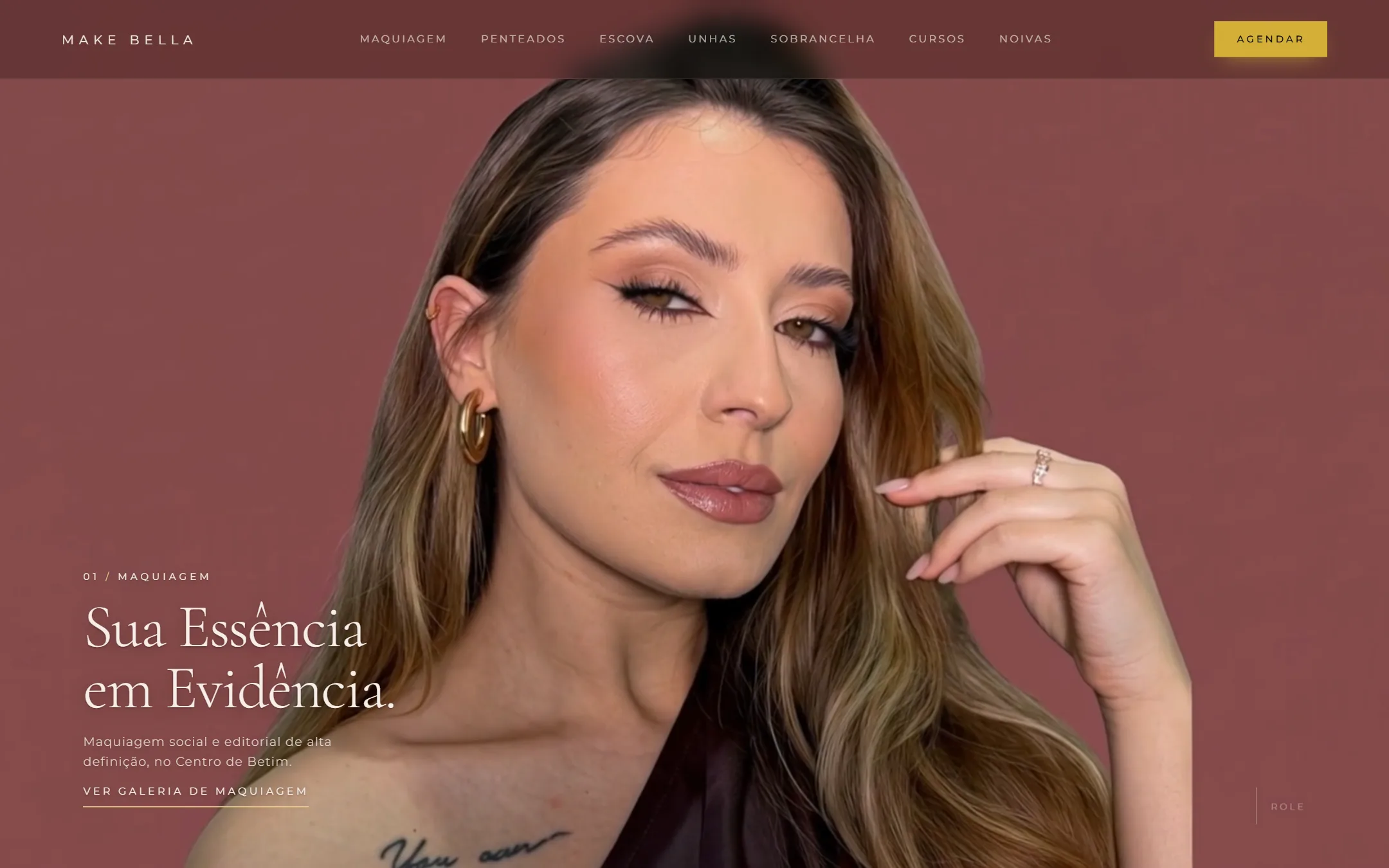 Página inicial da Make Bella no computador: retrato com maquiagem sobre fundo vinho e o título Sua Essência em Evidência.